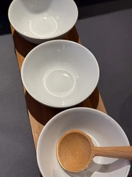 Three empty white ceramic bowls on a wooden serving board with a spoon, clean Foto stock
