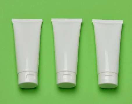 Three empty white plastic tubes for cosmetics or cream arranged in a row on.. Stock Photos