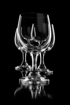 Three empty wine glasses on black one by one Stock Photos