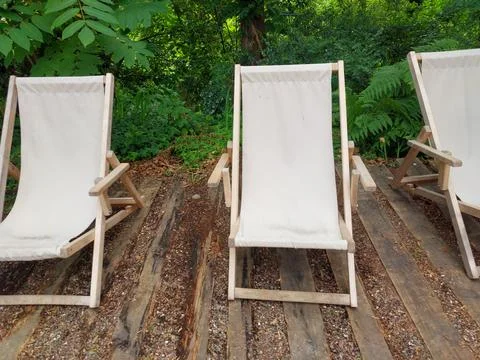 Three Empty Wooden Deck Chairs in a Green Garden Stock Photos