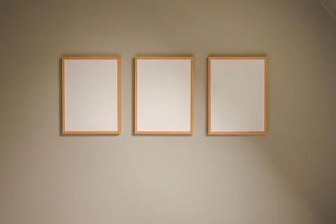 Three empty wooden frames on a subtle beige wall, minimalistic interior art.. Stock Photos