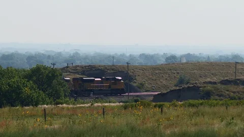 Three engine freight train rolls through grasslands and bluffs out west Stock Footage 86540669
