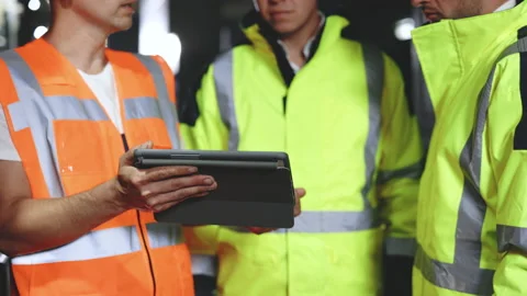 Three engineers men in uniform discuss use tablet, browsing building project Stock Footage 194626517