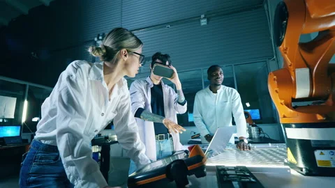 Three engineers at robotics development laboratory. Male engineer in VR headset Stock Footage 145598208