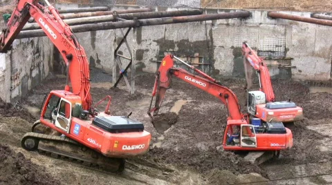Three excavators dig earth on construction Stock Footage