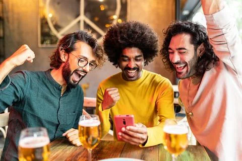 Three excited multiracial friends celebrating winning online bet on match Stock Photos