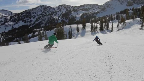 Three expert skiers pass camera fast as it follows them down a Utahs ski area. Video stock 99471610