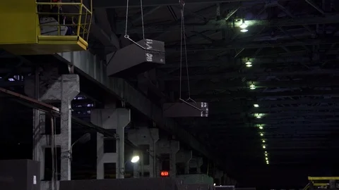 Three factory cranes in dark workshop transport graphite bars, around the rust Stock Footage 115926264