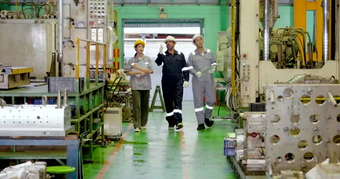 Three factory staff walk through industrial workshop in slow motion carrying Video stock 335115015