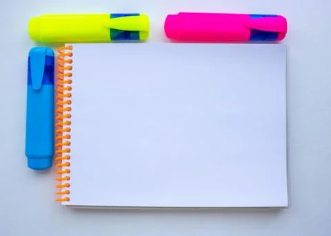 Three felt-tip pens and a Notepad with an orange spiral.School supplies Stock Photos