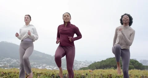 Three female friends doing high-knee steps on deck with yoga mats, maroon center Stock Footage 340675578