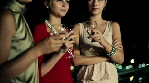 Three female friends enjoying night party on the terrace, crane shot Stock Footage