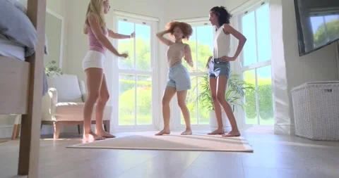 Three female friends facing bay windows, dancing on rug, taking hands, spinning Stock Footage 335987246
