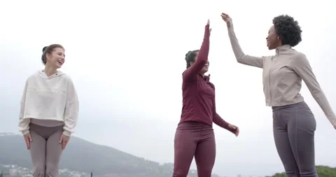 Three female friends post-run in leggings high-fiving clapping laughing on Stock Footage 340751329