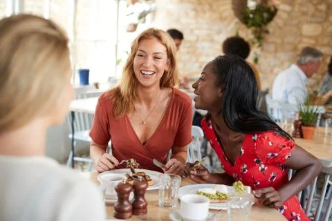 Three female friends talking over brunch at a cafe, close up Stock Photos