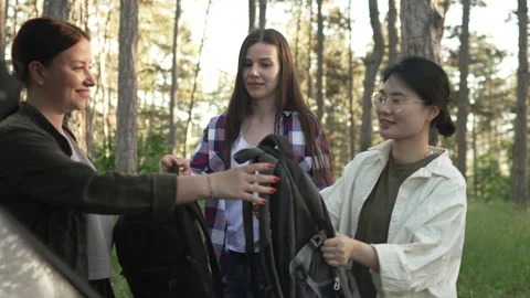 Three female friends unloading backpacks from a car for a hike Stock Footage 335843816