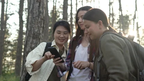 Three female friends using a smart phone for navigation in the forest Video stock 335842185