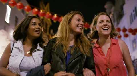Three female friends walking through a festival district at night in the city Stock Footage 67748827