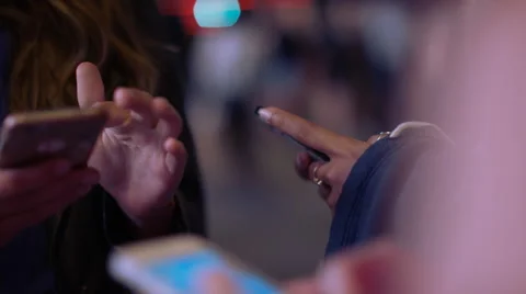 Three female hands on their phones in the city at night, in slow motion Stock Footage