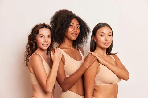 Three female models with different skin colours pose in the studio on white Stock Photos