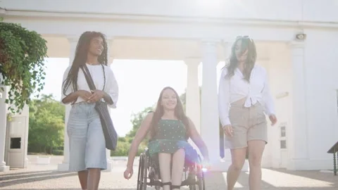 Three female multiracial friends one disabled woman in a wheelchair enjoying a Stock Footage 313400161