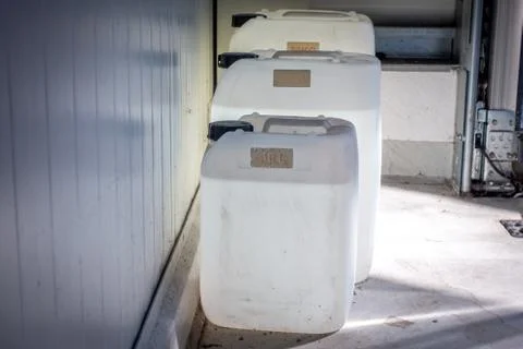 Three filled white canisters of different sizes standing on a wall in a works Stock Photos