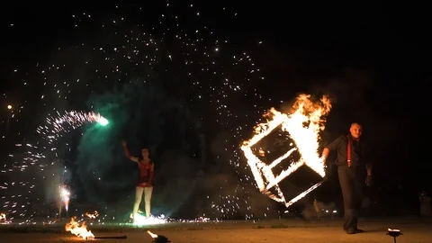 Three fire show performers standing in fire circle, performing. One juggles 動画素材 101048178