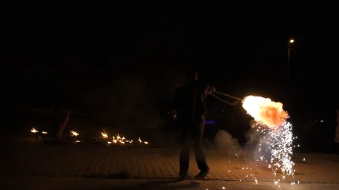 Three fire show performers standing in fire circle, performing. One juggles 動画素材 101048337