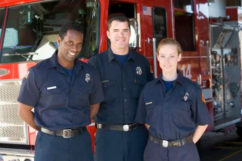 Three firefighters standing in front of fire engine Stock Photos