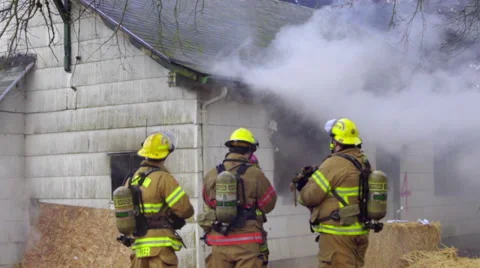 Three firemen stand outside a burning house Stock Footage 60762110