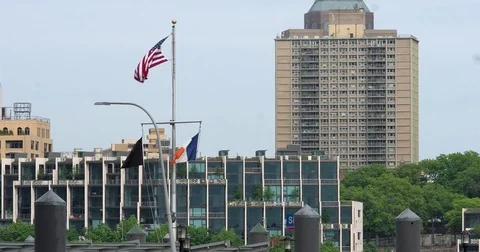 Three flags flutter on the mast over the Pier 11 Ferry Terminal in Manhattan Stock Footage 77519201