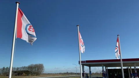 Three flags futter in the wind and a pen to a Esso pumping station. Stock Footage 149372254