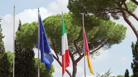 Three flags waving in wind against blue sky. Close up of Italian, EU and flag of Stock Footage 148892106