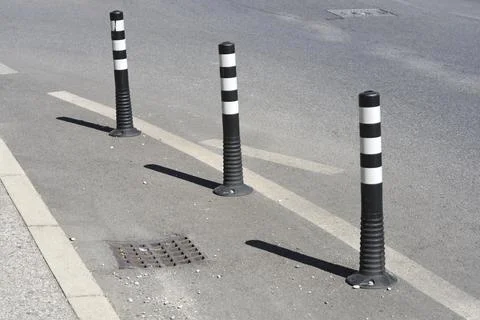 Three flexible black and white plastic traffic bollards on asphalt Stock Photos