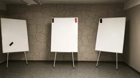 Three flip chart boards set up in empty classroom with stone wall background. Stock Photos