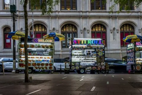 Three food carts line a city street under umbrellas Foto stock