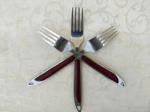 Three forks arranged in a star pattern on a table Stock Photos