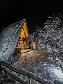 Three A Frame Cabins with Lights in Winter Forest Stock Photos
