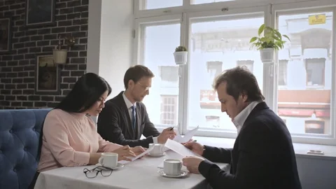 Three freelancers signing up contract documents and shaking hands. Stock Footage 130043809