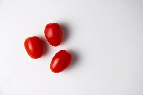 Three fresh cherry tomatoes resting on white background Stock Photos