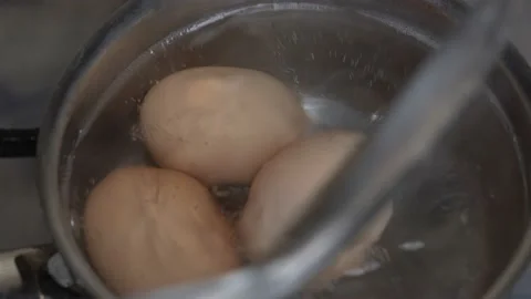 Three fresh chicken eggs boiling in stainless steel pan, close up, top view Stock Footage 146394925
