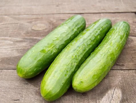Three fresh cucumber lying on an old wooden background Foto stock