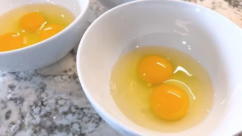 Three Fresh Eggs Cracked Open in a White Bowl for Cooking Foto stock