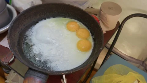 Three Fresh Eggs Frying in Cast Iron Skillet During Outdoor Camping Stock Footage 341993940