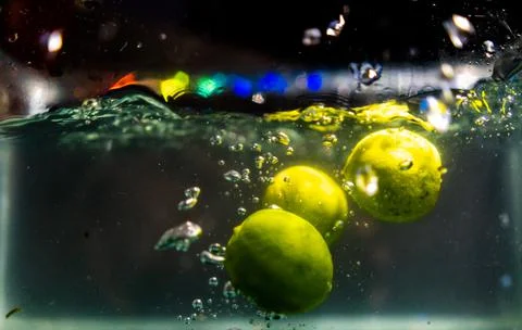 Three fresh limes falling deep in water with splash Stock-Fotos