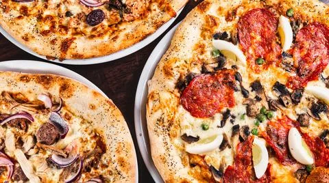 Three fresh made delicious pizzas of various types Stock Photos
