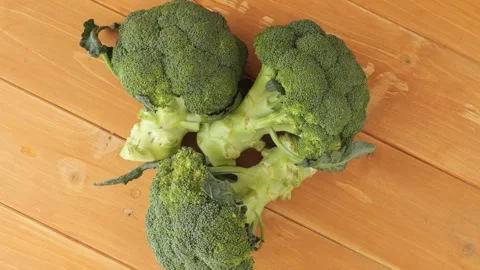 Three fresh raw broccoli rotating on a wooden table Stock Footage 339366955