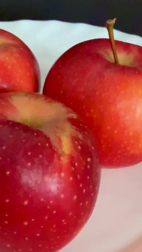 Three fresh red apples resting on white ceramic plate Stock Footage 331973919