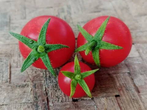 Three fresh red cherry tomatoes on a bamboo mat Stock Photos