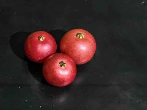 Three Fresh Red Pomegranates with Dramatic Shadows on Dark Background Stock Photos